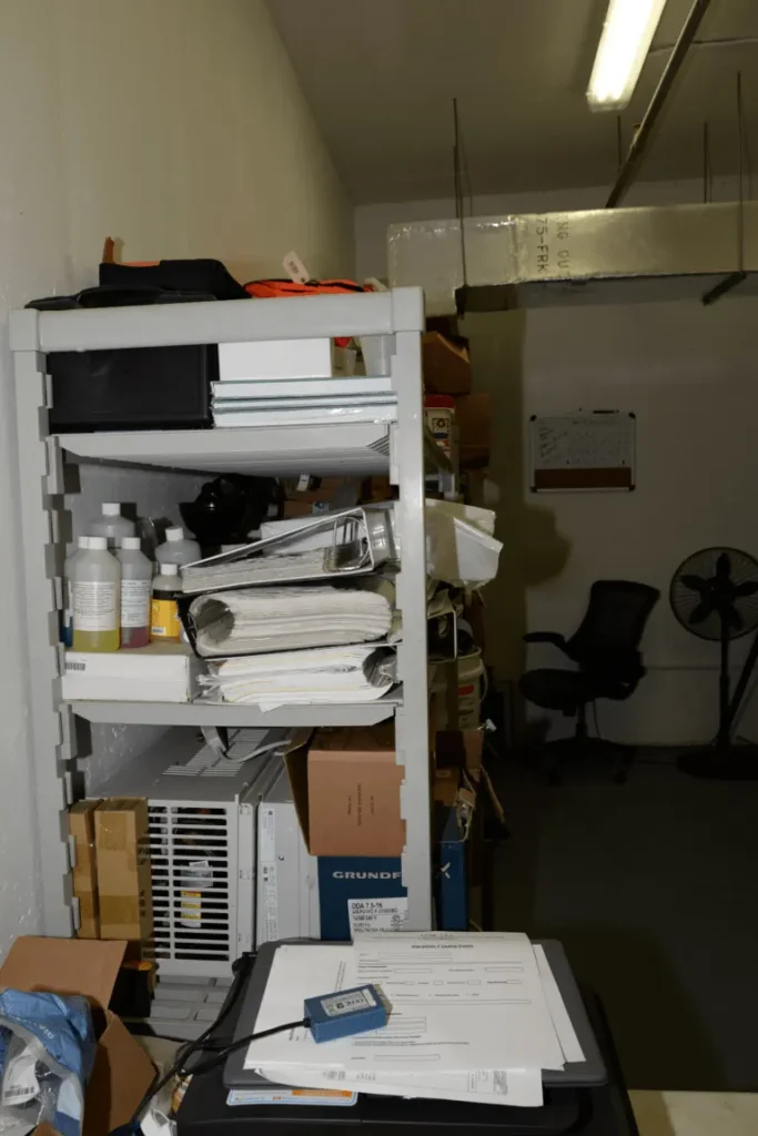 Why a cubicle feels heavy — cluttered office shelves and boxes (Wikimedia Commons)